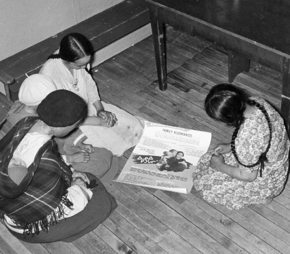 Women looking at a family allowance poster, Baker Lake (Qamanittuaq), Nunavut, by unknown photographer, Health and Welfare Canada (MIKAN 3613868)