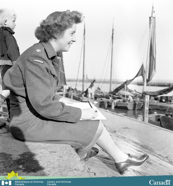 Black-and-white photograph taken from the side showing a smiling woman in uniform sitting on a pier with a drawing tablet and pencil in hand. In the background, there is a young blond child and sailboats docked nearby.