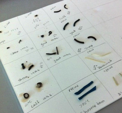 Colour photograph showing a piece of paper that has been marked out into squares with leather samples in each square. Each square shows the pre- and post-shrink test samples. 