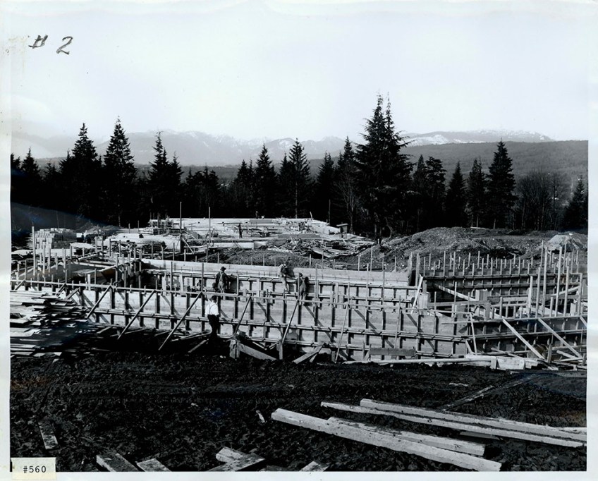 A black-and-white photograph of a construction site showing wooden forms and supports.
