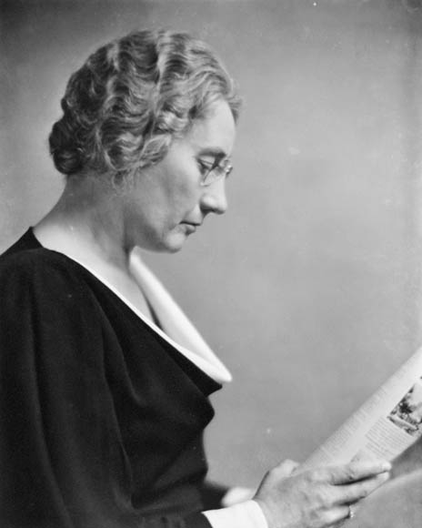 A black-and-white photograph of Agnes Macphail in profile, reading the paper.