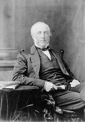 A black-and-white photograph of a man sitting at a desk, holding a letter.
