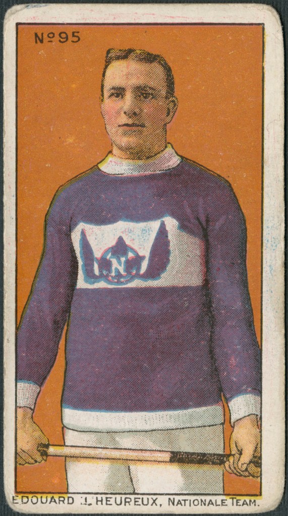 A trading card with a colour print of a man wearing a purple sweater with white trim and holding a lacrosse stick with both hands. On the sweater is a purple maple leaf with purple wings and adorned with a white “N.” It is captioned: “Edouard L’Heureux, Nationale Team.”