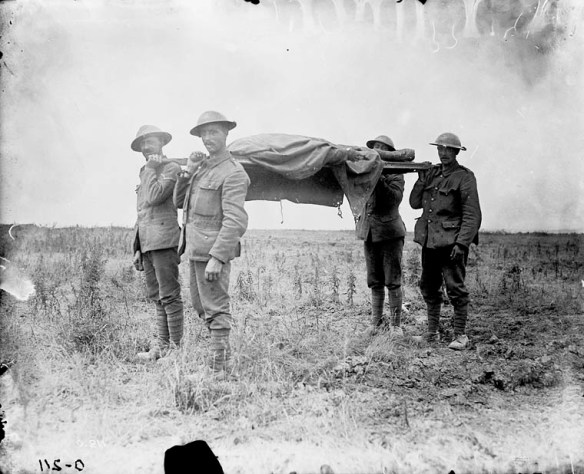 A black-and-white photograph of four soldiers carrying a stretcher with a shrouded body on it through a devastated landscape.