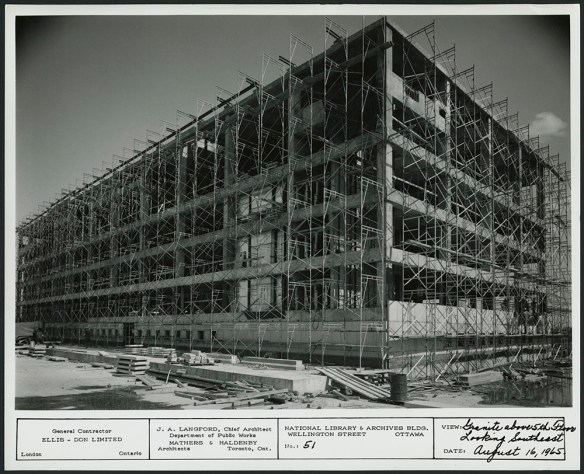 A black-and-white photograph showing a building completely surrounded by scaffolding.