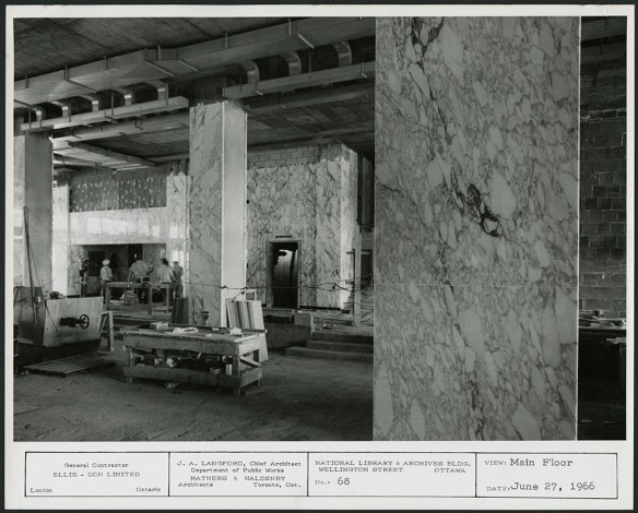 A black-and-white photograph showing a partially completed interior covered in deeply-veined, white Carrera marble.