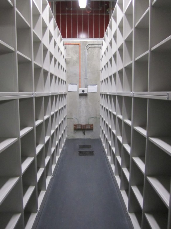A hall, inside a building, with white shelving on both sides.