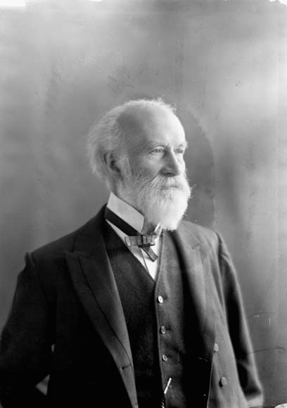 A black-and-white photo of an older man wearing a suit jacket, waistcoat and bow tie.