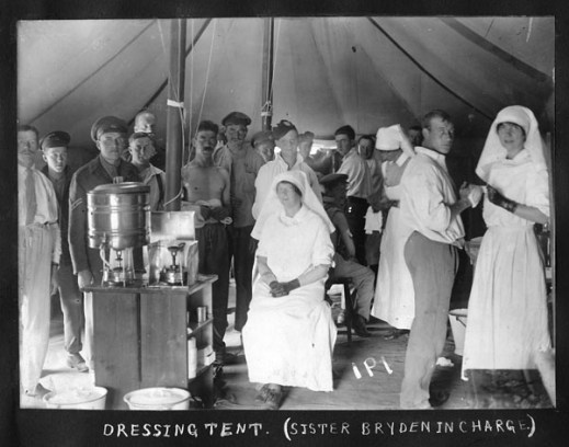 A black and white photograph of a group of soldiers and nursing sisters in a tent.