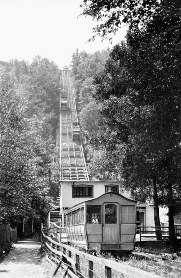 A black-and-white photograph of a funicular. One tram is going up the hill and the other is going down.