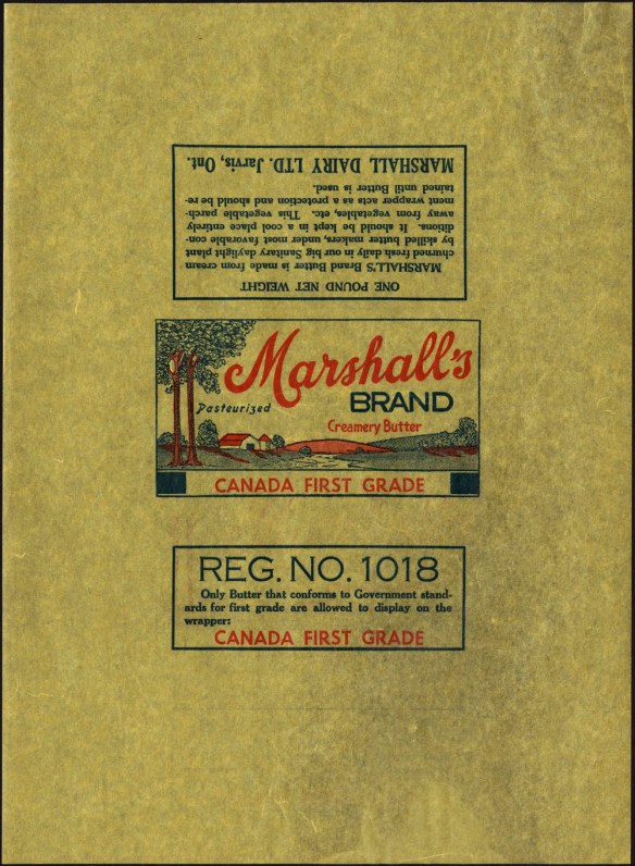 A colour wax-paper wrapper with a picture of a farm with trees. The text above the image reads: “Marshall’s Brand. Creamery Butter. Pasteurized. Canada First Grade.” Another text box (on the wraparound portion of the paper) reads: “Reg. No. 1018. Only butter that conforms to Government standards for first grade are allowed to display on the wrapper CANADA FIRST GRADE.”