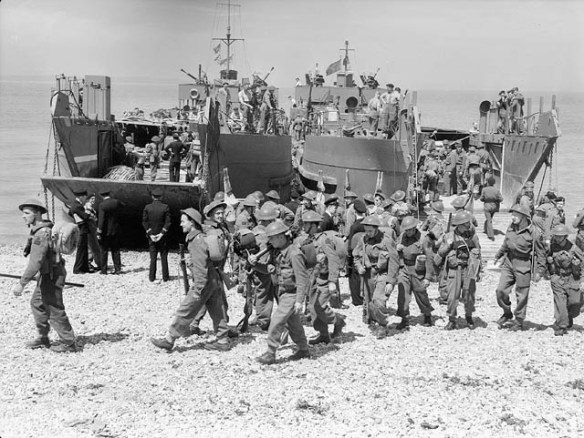 A black-and-white photograph of a practice landing, with soldiers leaving the landing craft and walking on the beach in orderly groups.