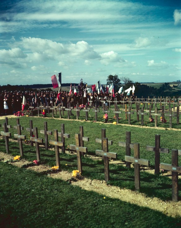 A colour photograph of a ceremony alongside rows of temporary grave crosses at the Dieppe Canadian Military Cemetery near Dieppe, France.