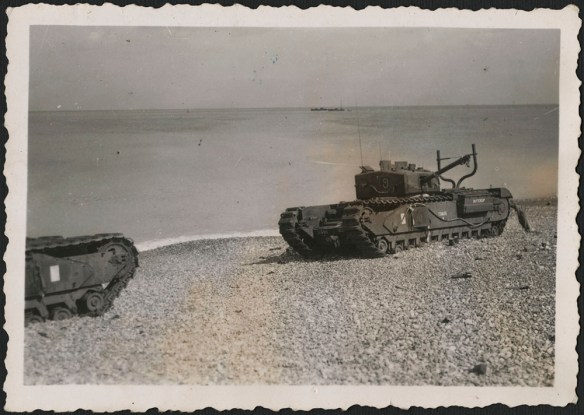 A black-and-white photograph of disabled or abandoned tanks on the beach at Dieppe. One tank has “Buttercup” painted on its side, among other recognition markings.