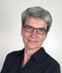 A colour photograph of a woman wearing glasses looking directly at the viewer