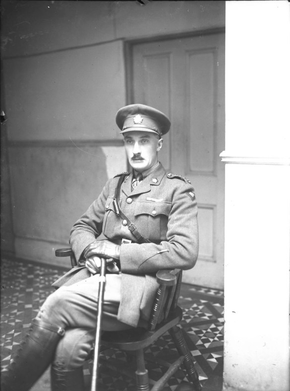 A black-and-white photograph of a seated officer wearing a cap and all the accoutrements of an officer.