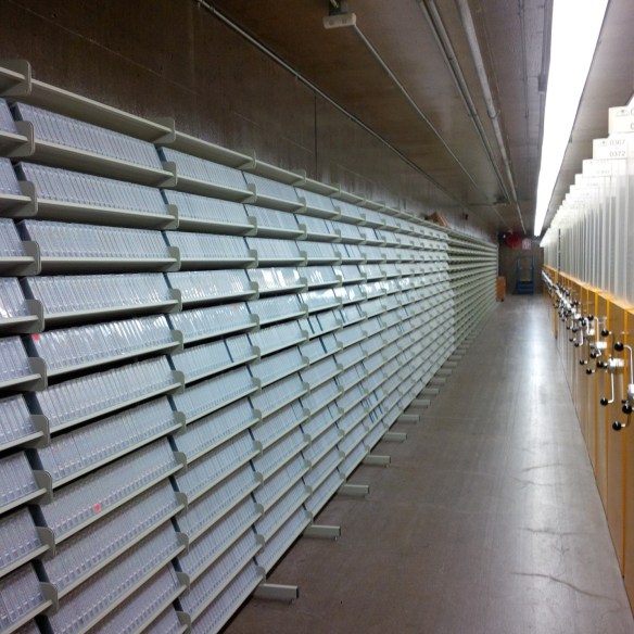 A colour photograph of a long white shelf on the left and high-density storage on the left.