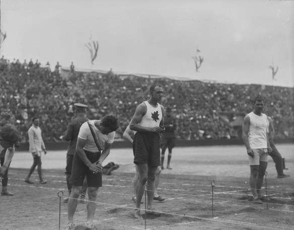 A black-and-white photograph of a group of runners at the starting line. One is wearing a white shirt with a maple leaf on the front.