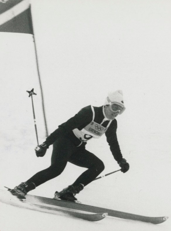 A black-and-white photograph of Nancy Greene during her gold medal run in giant slalom.