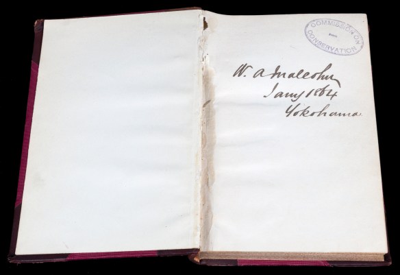 A colour photograph of two pages of an open book showing a stamp and a signature on the right-hand page. 