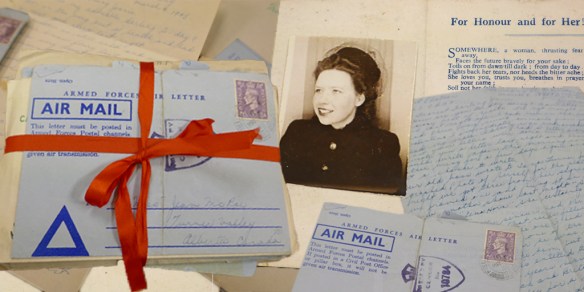 A colour photograph of piles of letters, with one bundle held together by a red ribbon. Underneath them is a photograph of a young woman wearing a coat and stylish hat.