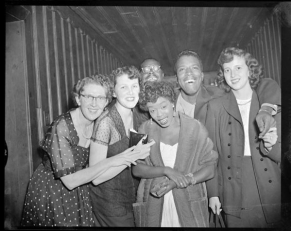A black-and-white photograph of five young people gathered around American jazz singer Sarah Vaughan to have their picture taken.