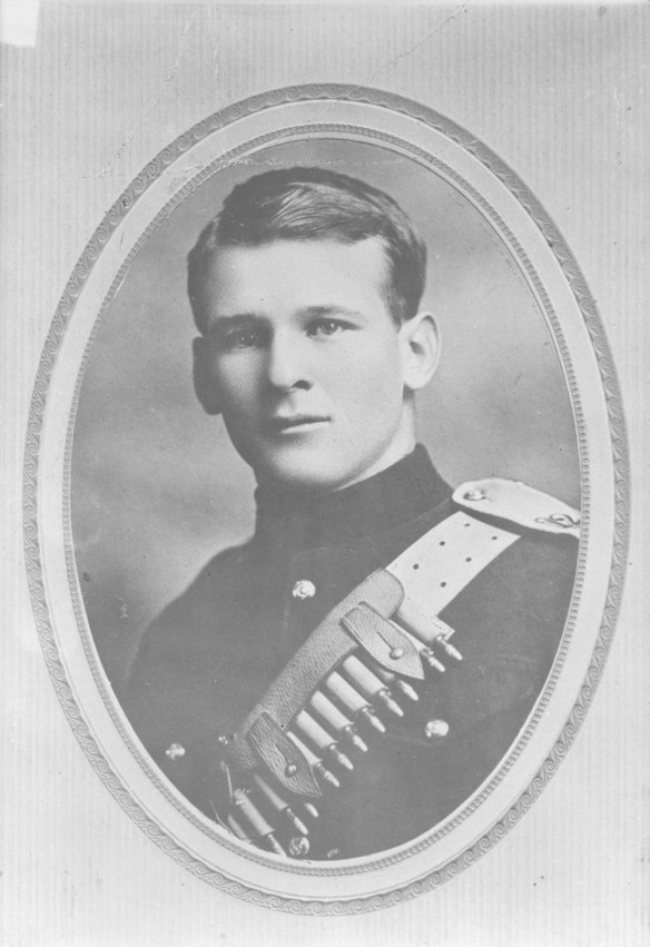 A black-and-white bust photograph of a soldier wearing a light coloured non-commissioned officer (NCO) belt with bullets across his chest. 