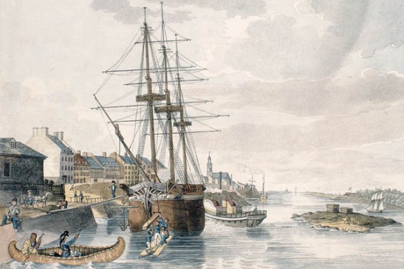 A colour print of Montréal harbour and a moored sailing ship having its cargo unloaded onto the wharf. There is a paddleboat to the ship’s port side, and two men paddling a canoe across its bow. 