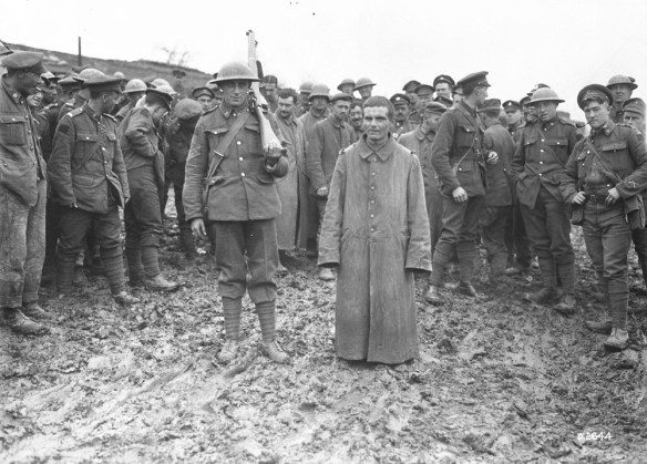 A black-and-white photo showing a group of soldiers surrounding a recently captured enemy combatant. 
