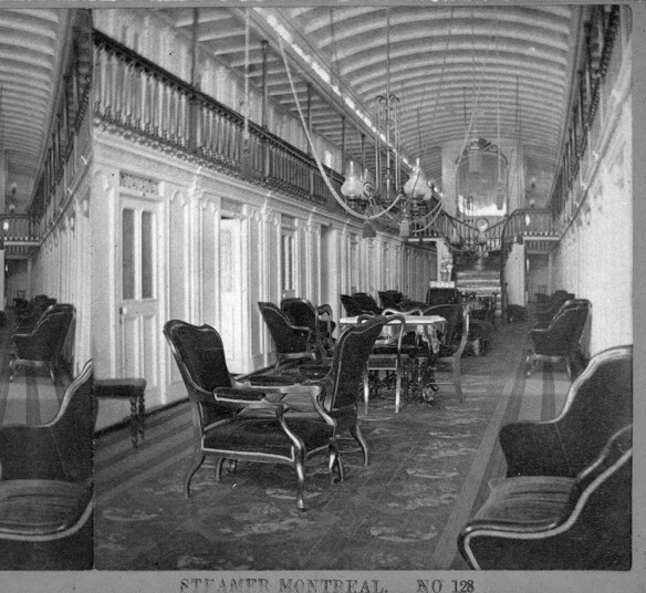 A black-and-white photograph of the interior of the steamer Montreal, showing a large carpeted sitting room with numerous cushioned chairs.