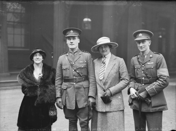 A black-and-white photograph of four people standing and looking toward the camera.