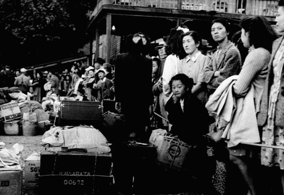 A black-and-white photograph of a group of women with a child standing in front of luggage and crates.