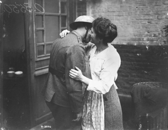 A black-and-white photograph of a woman in a white blouse with her arms around a soldier in uniform, kissing his cheek.