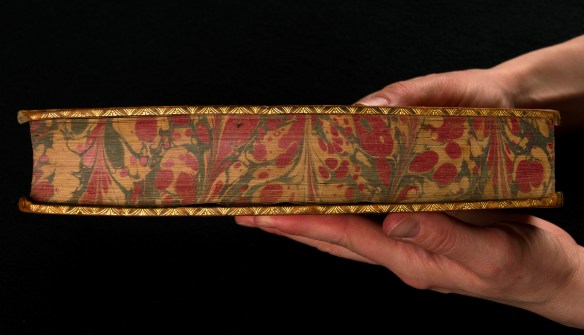 A close-up colour photo of hands holding an elaborately decorated book.