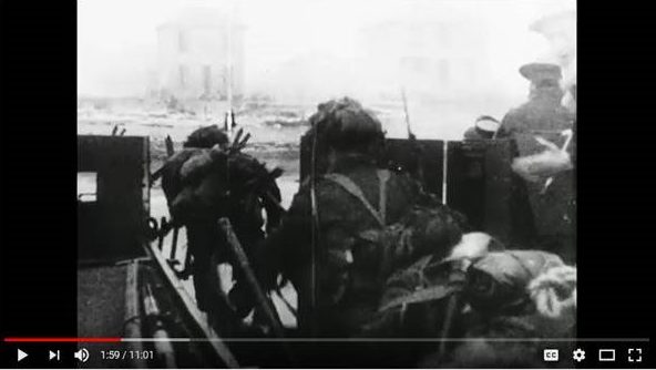A black-and-white image taken from moving film, showing soldiers exiting a landing craft.