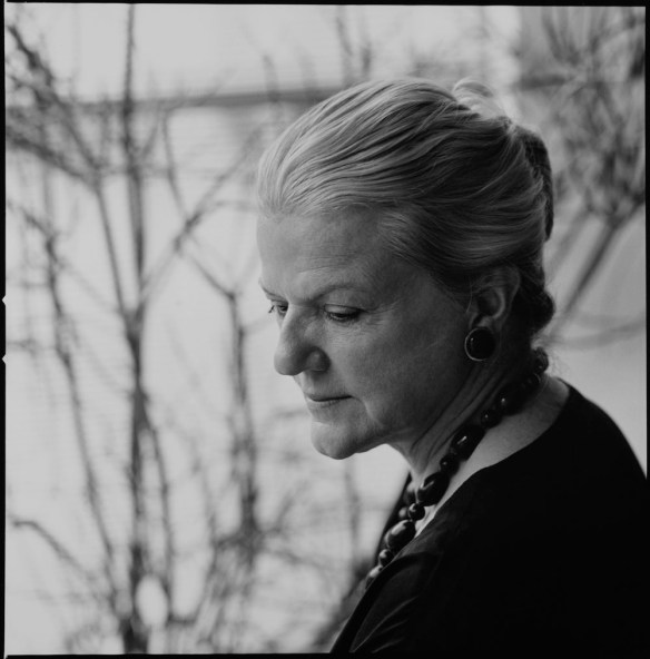 Black-and-white photograph of a woman in profile with grey hair and a dark necklace. 