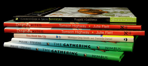 Colour photograph of six books placed in a stack.