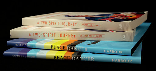 Colour photograph of four books placed in a stack.