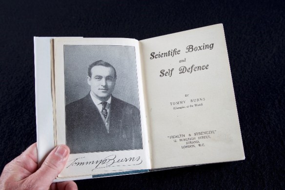 Black-and-white photo of a hand holding a book open at the title page.