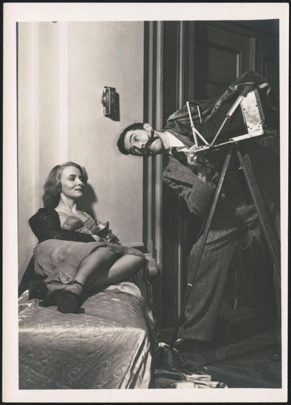 A black-and-white photograph of Brodie Macpherson pretending to photograph a reclined Miss 1948, Lialla Raymes.