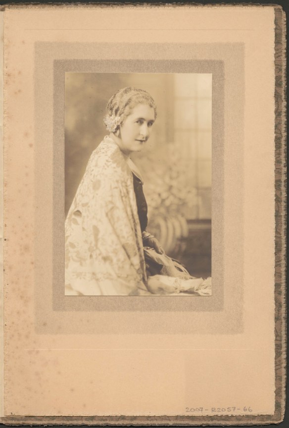 Side portrait of Madge Macbeth wearing a pale patterned cape. 