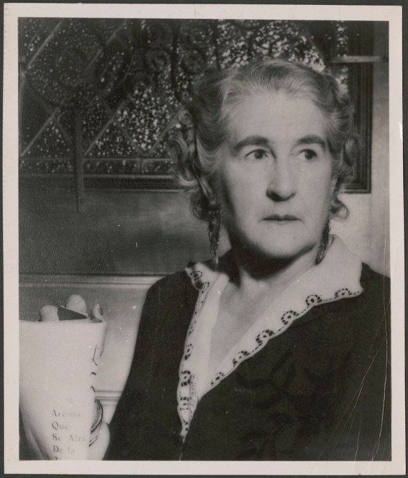 Madge Macbeth holding a document and looking off to the side. 
