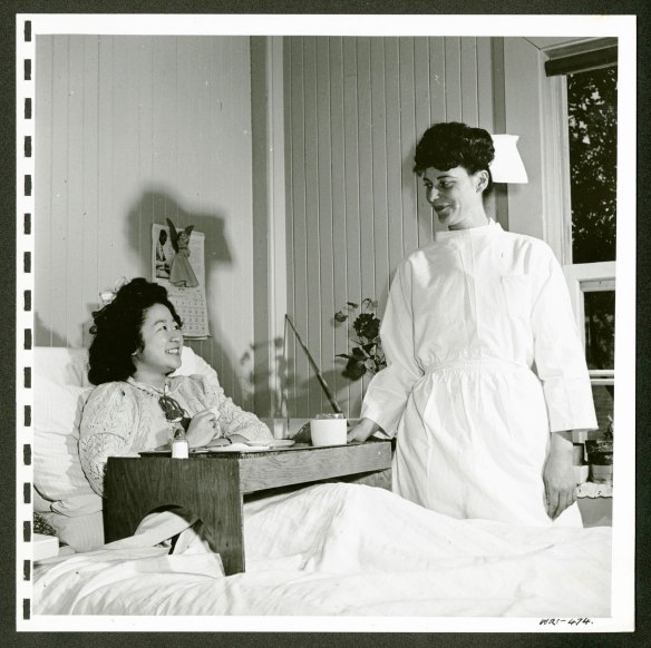 From left to right: Hospitalized woman (internee) in bed. Nurse standing on the right.