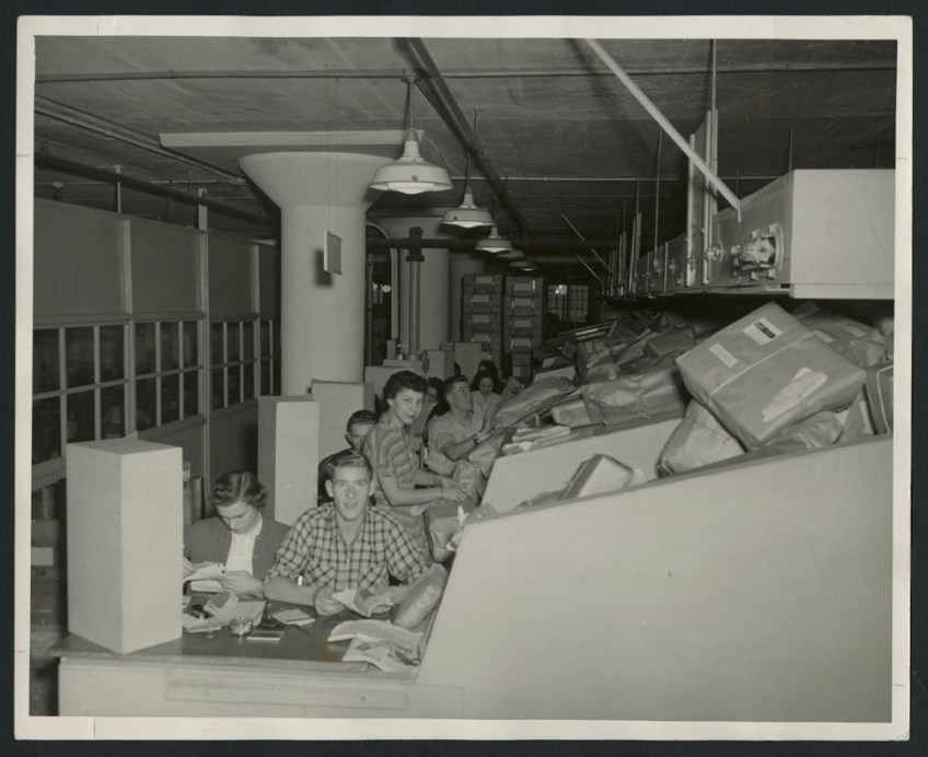 Two black-and-white photographs, one showing a group of employees sorting parcels into bins, and the other showing women at desks checking addresses on parcels as the parcels slide down a ramp toward them.