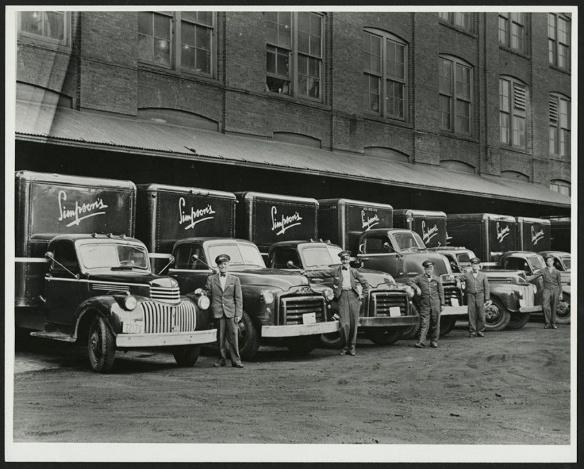 Three black-and-white photographs showing men dressed in uniforms beside Simpson’s delivery trucks, over the decades.
