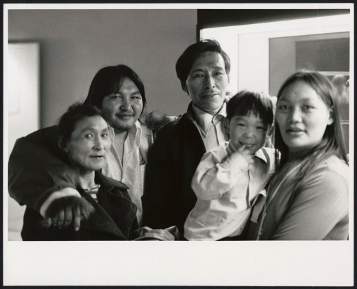 A black-and-white photograph of four adults and a child smiling at the camera.