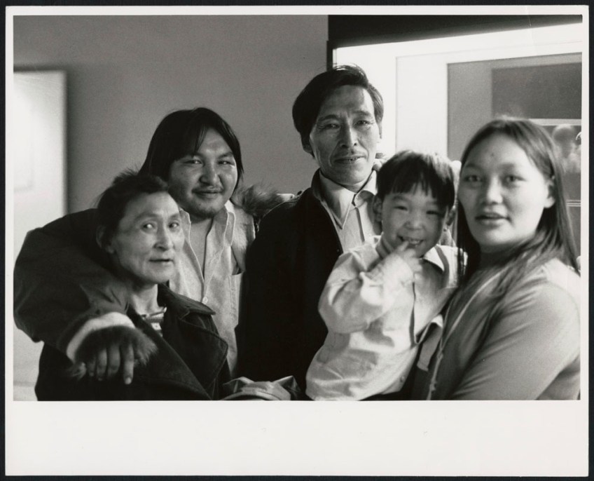 A black-and-white photograph of four adults and a child smiling at the camera.