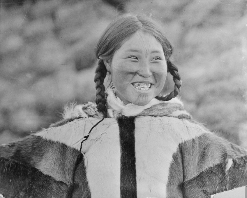 A black-and-white photograph of a smiling Inuk woman with facial tattoos.
