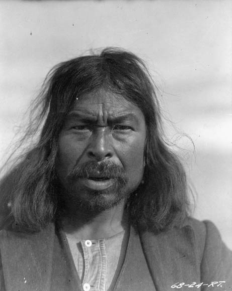 A black-and-white photo of a man with long hair and a mustache.