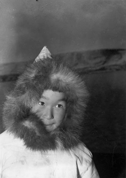 Black-and-white photo of a young boy wearing a fur-lined hood.